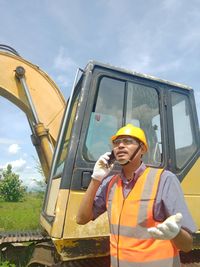 Man working on yellow motorcycle against sky