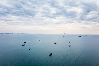 Aerial seascape view and small container ship floating in sea horizon and cloud sky background 