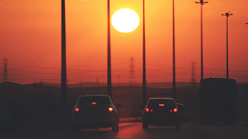 Street lights against orange sky during sunset