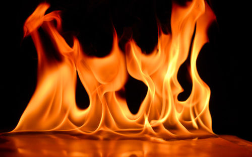 Close-up of lit candle against black background