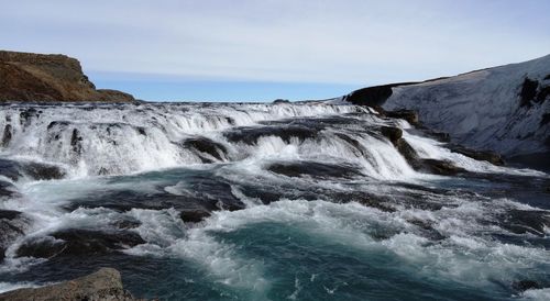 Scenic view of waterfall against sky