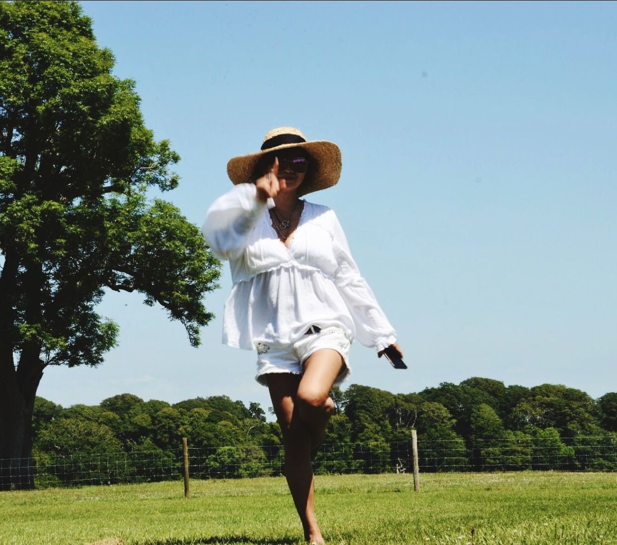 plant, hat, real people, one person, tree, leisure activity, lifestyles, young adult, casual clothing, nature, land, grass, field, day, standing, front view, sky, young women, sunlight, fashion