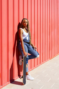 Portrait of young woman standing against yellow wall