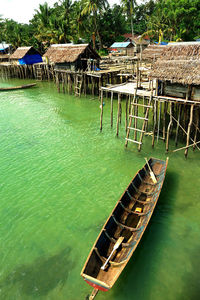 Stilt house in sea against buildings