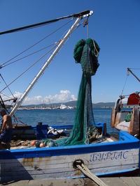 Fishing boats moored at harbor against clear blue sky