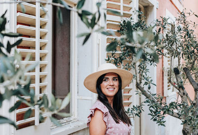 Beautiful young woman standing under olive tree, fashion, summer, happy, smiling, lifestyle.