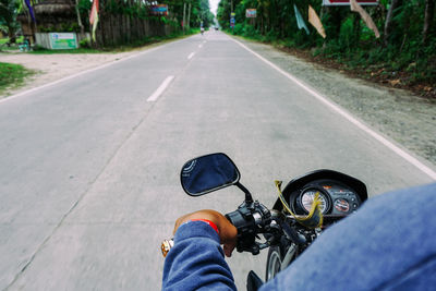 Midsection of man riding motorcycle on road