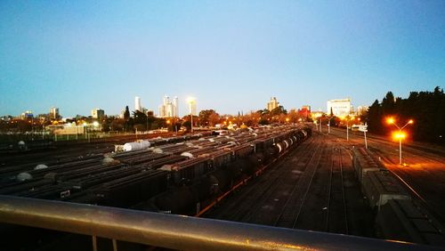 Train on illuminated railroad tracks against sky in city