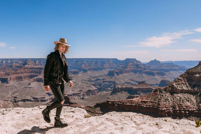 Man standing on rock against sky