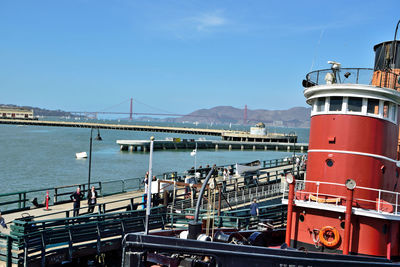 Boats moored at harbor against blue sky