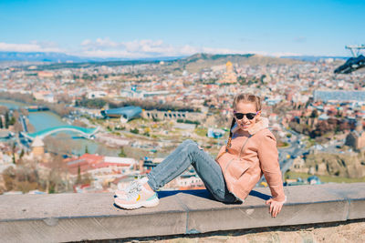 High angle view of woman sitting on townscape against sky