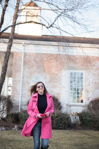 Portrait of woman in sunglasses walking against building