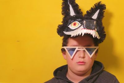 Portrait of boy wearing hat against yellow background