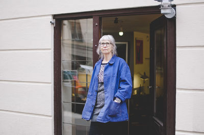 Senior female owner standing with hands in pockets outside jewelry store