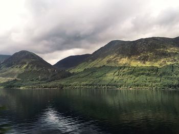 Scenic view of lake by mountains against sky