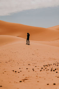 Full length of man on sand dune in desert against sky