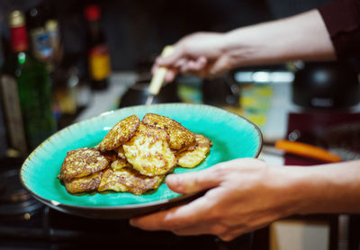 Midsection of person holding bread in plate on table