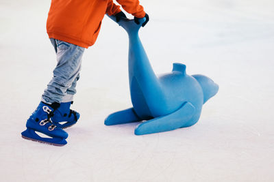 A child pushing a blue seal toy on an ice rink