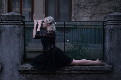 Full length of young woman sitting on gate