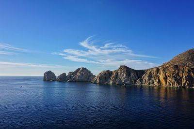 Scenic view of sea and mountains against blue sky