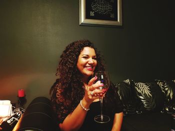 Portrait of smiling woman having wine at home