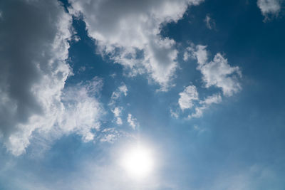 Low angle view of sunlight streaming through clouds