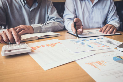 Midsection of businessmen working over graph in office