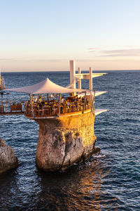 Groyne in sea against clear sky during sunset