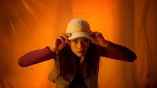 Portrait of young woman standing against yellow wall