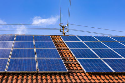 Solar panels of a photovoltaic system on a private house roof with power pole and power cables