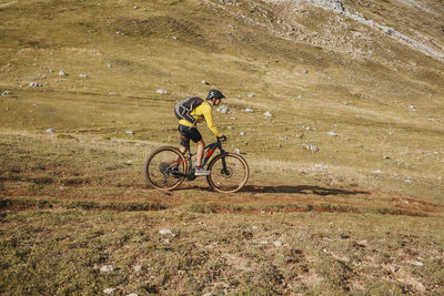 Mid adult woman riding electric bicycle on mountain at somiedo natural park, spain