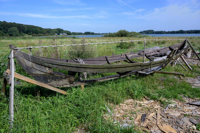 Abandoned boats on field against sky