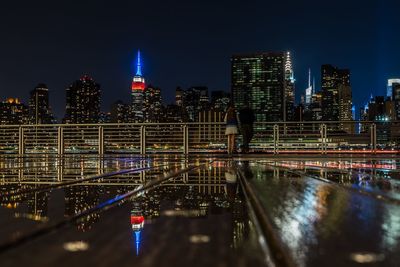 Rear view of man and woman at gantry plaza state park in city during night