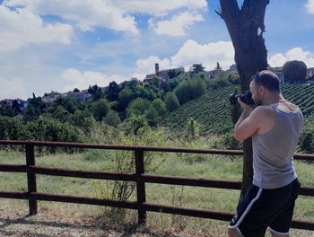 Side view of man standing by railing against trees