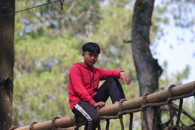 Side view of young man standing against trees