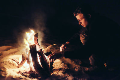 Man looking at bonfire during night