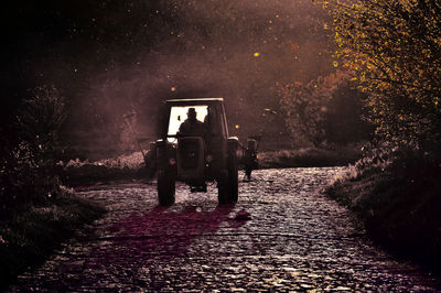 Rear view of man walking on footpath at night