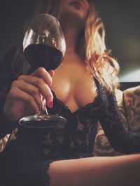 Low angle view of sensuous woman holding wineglass at home