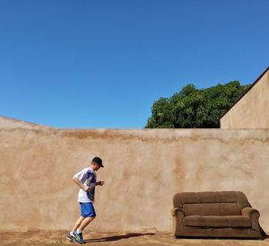 Full length of man running against blue sky