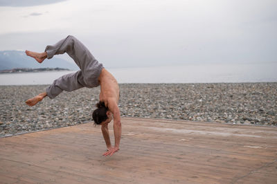 Athlete practicing handstand at beach