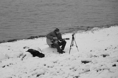 Man sitting at beach during winter