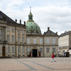 Buildings in city against cloudy sky