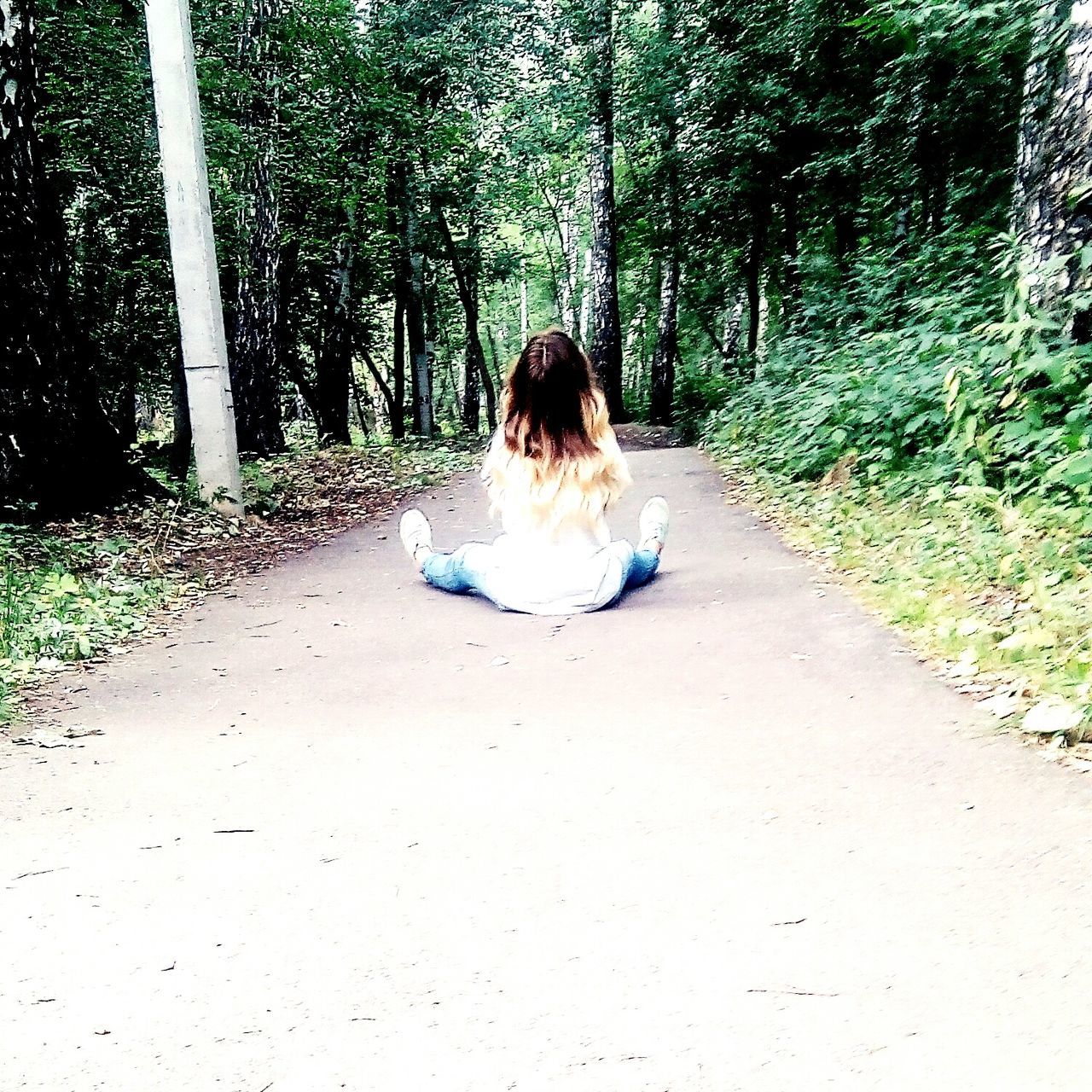 WOMAN SITTING ON TREE TRUNK IN FOREST