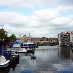 Boats in harbor against cloudy sky