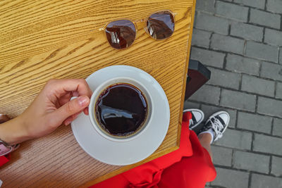 Cropped hand of woman holding coffee on table