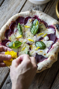 Cropped hand of person preparing pizza