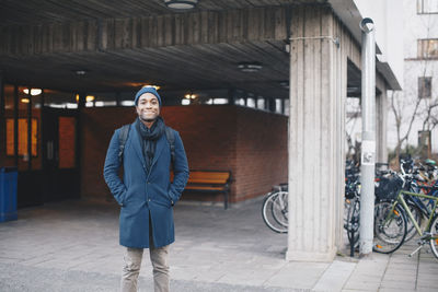 Portrait of happy man wearing standing against building in campus