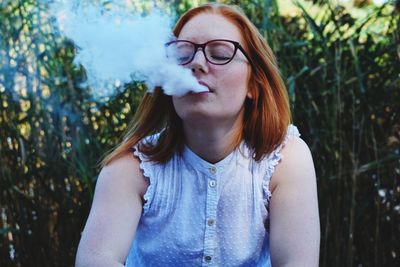 Portrait of beautiful young woman standing against plants