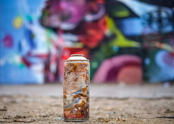 Low capture of rusty spray can with graffiti on background 