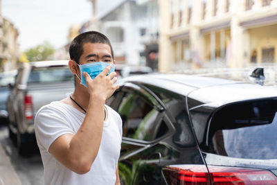 Portrait of young man standing in car